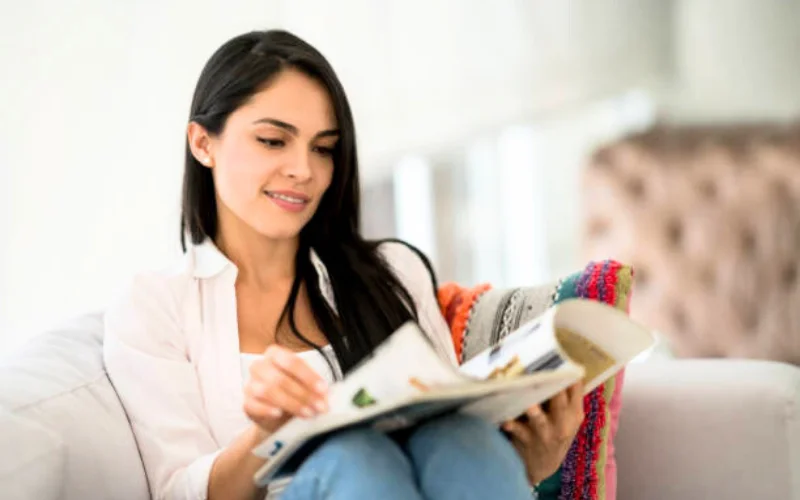 Happy middle-aged woman reading book without glasses after using VisiSharp eye supplement for vision improvement