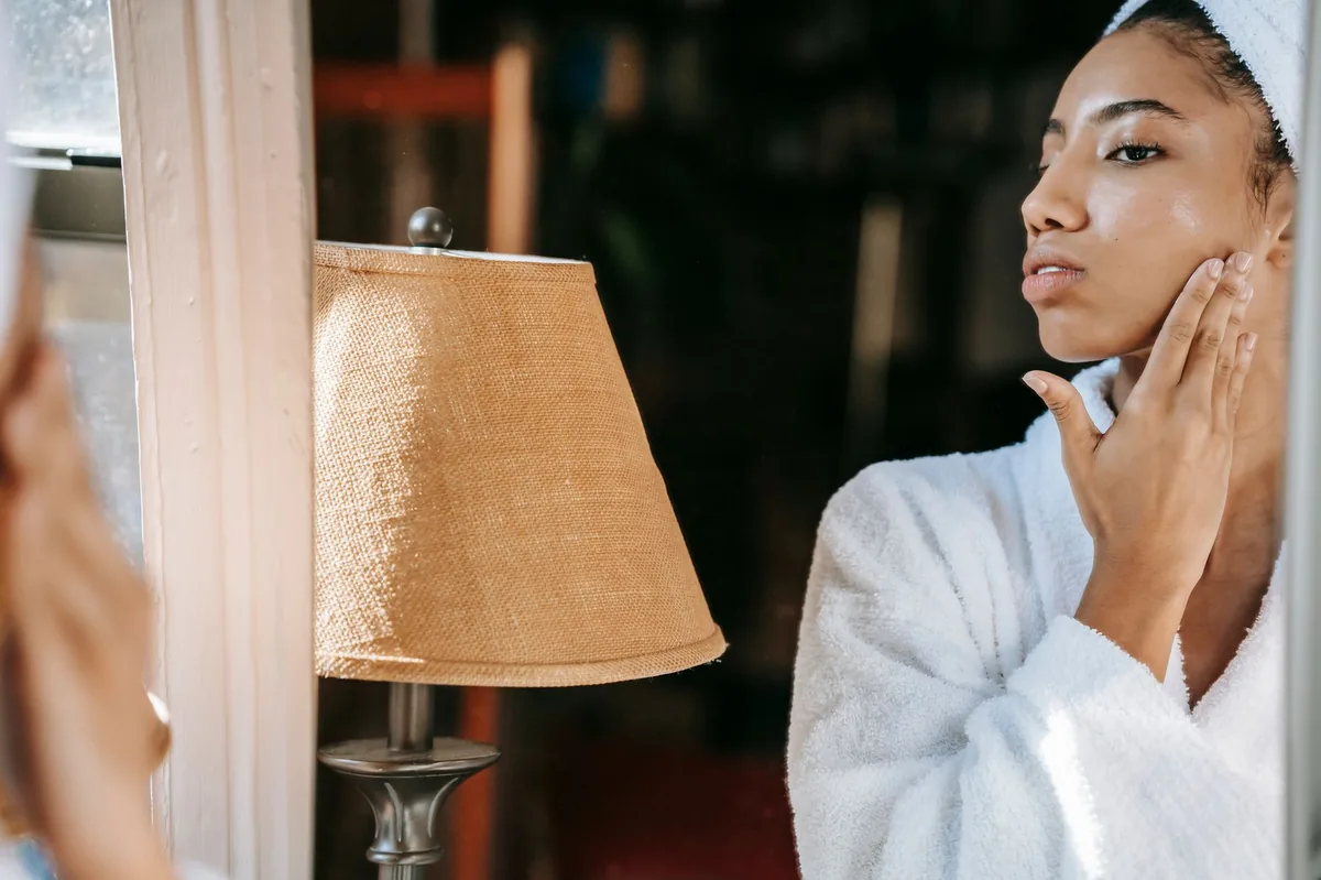 Woman examining her face in a mirror — the truth about "cortisol face"