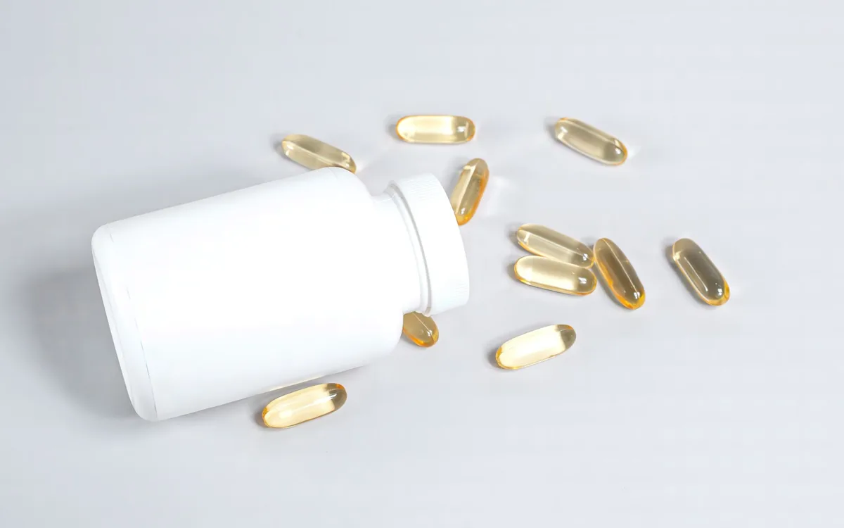 Supplement capsules spilling from a white bottle — magnesium glycinate for sleep